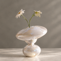 MARVOLM tilted disc and hourglass sculptural vase on dining table with daisy and wild flower stems beside stone bowl — More Than a Vase, a statement piece bringing art, emotion and serenity into everyday life